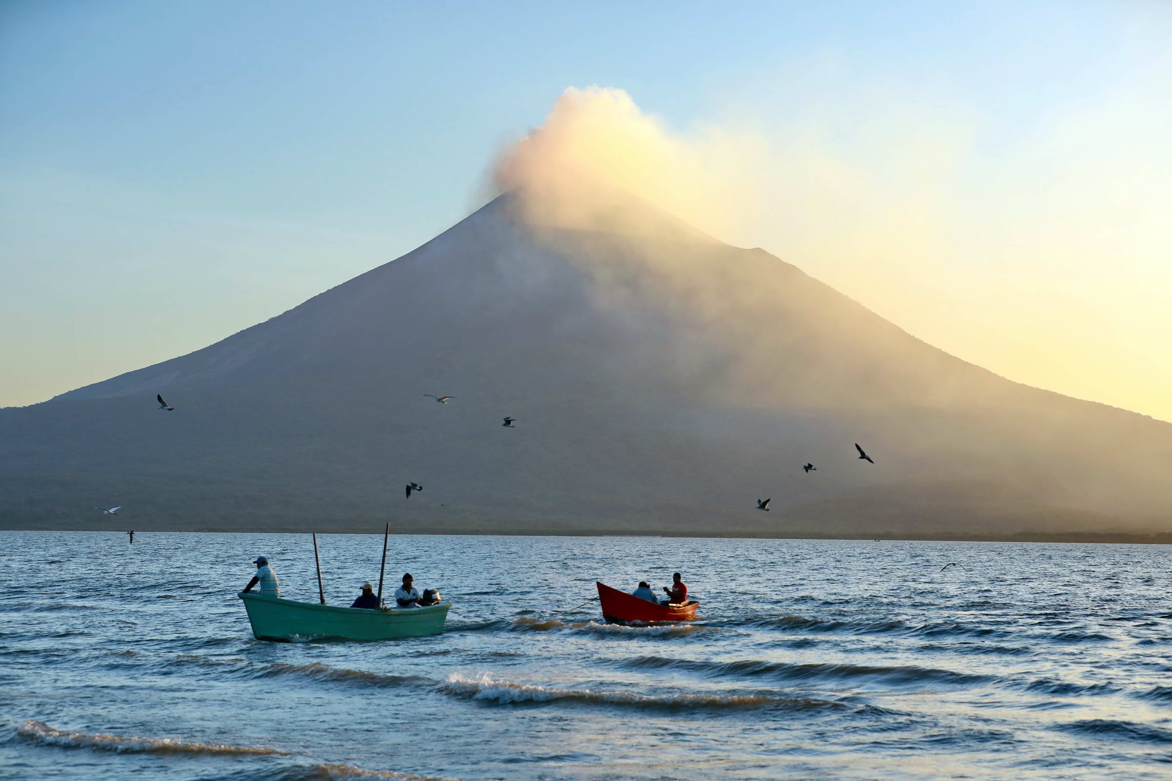 rauchender Vulkan und Fischerboote
